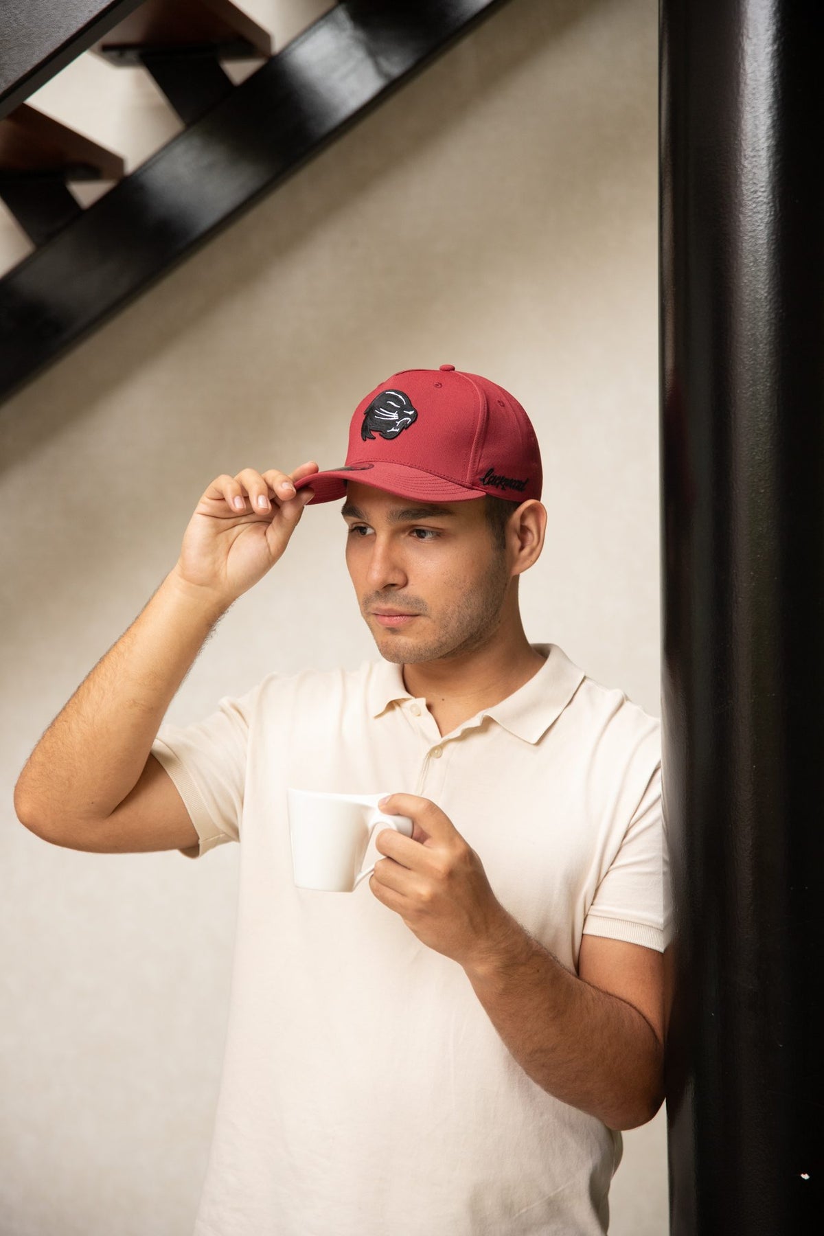 Model wearing a burgundy cap with an embroidered panther patch