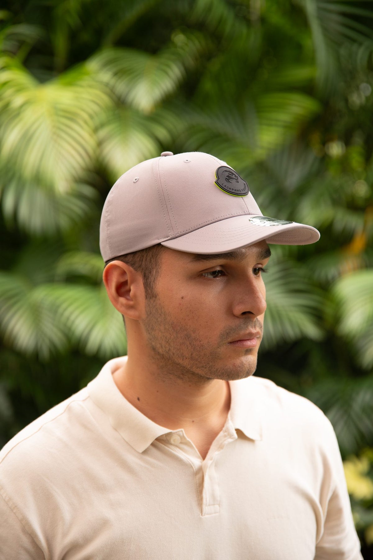 Model wearing a light grey cap with a rubber Lackpard Fashion patch